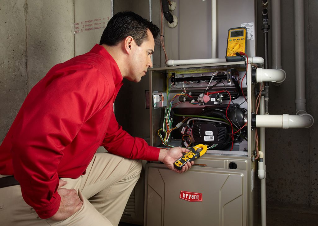 Heating and air conditioning technician servicing an indoor furnace in Queen Creek, AZ