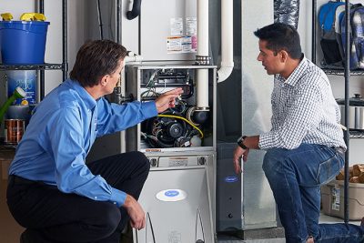 HVAC technician explaining furnace repair and maintenance to a homeowner in Queen Creek, AZ