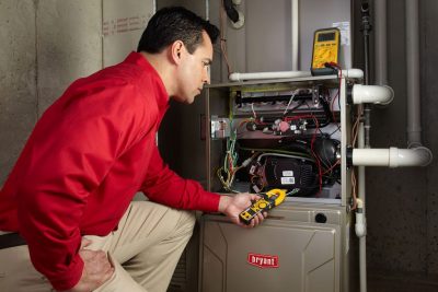 Heating and air conditioning technician servicing an indoor furnace in Queen Creek, AZ